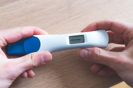 Woman hand holding pregnancy test, result is pregnant, "Schwanger"の写真素材