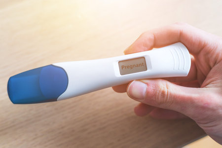 Woman hand holding pregnancy test, result is pregnant, "Pregnant"の写真素材