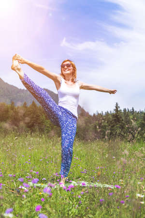 Young girl is doing yoga in the parkの写真素材