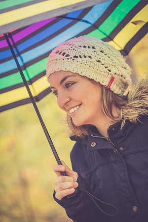 Young girl in blue coat and umbrella is taking a walk through the autumnal forestの写真素材