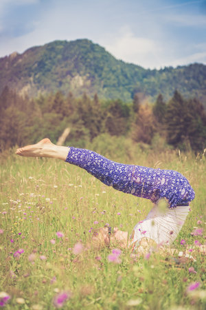 Young girl is doing yoga in the parkの写真素材