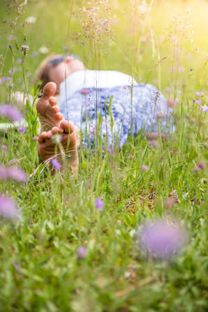 Young girl in park is lying in the grass, enjoying the dayの写真素材