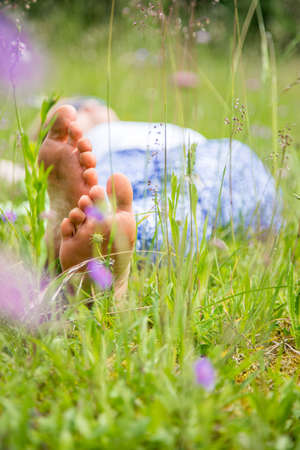 Young girl in park is lying in the grass, enjoying the dayの写真素材