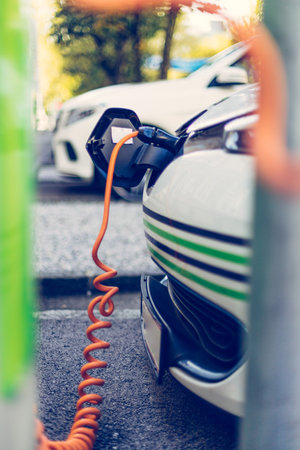 Electric car recharging with charge cable and plug leading to charge point.の写真素材