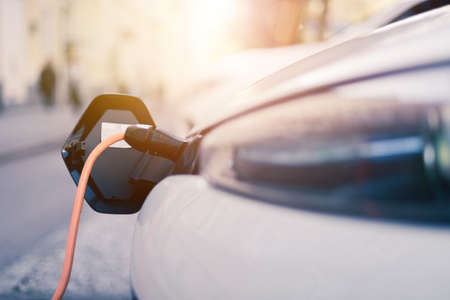 Electric car recharging with charge cable and plug leading to charge point.の写真素材