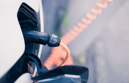 Electric car recharging with charge cable and plug leading to charge point.の写真素材