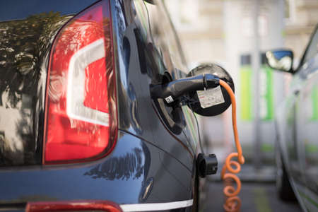 Electric car recharging with charge cable and plug leading to charge point.の写真素材
