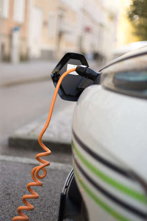 Electric car recharging with charge cable and plug leading to charge point.の写真素材