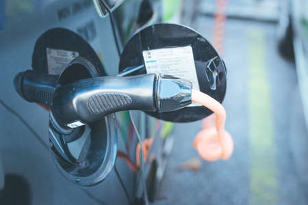 Electric car recharging with charge cable and plug leading to charge point.の写真素材