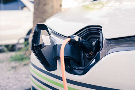Electric car recharging with charge cable and plug leading to charge point.の写真素材
