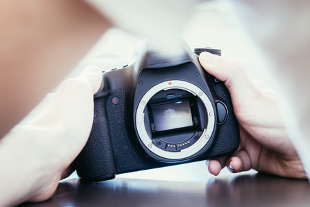 Hands of a photographer are touching a professional reflex camera, open sensorの写真素材