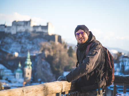 Young man in winter jacket is enjoying the view over Salzburg, historic centerの写真素材