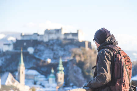 Young man in winter jacket is enjoying the view over Salzburg, historic centerの写真素材