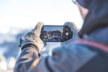 Young tourist man is making a photo of Salzburg with her smartphone, winter timeの写真素材