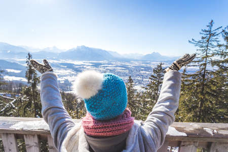 Back of young woman who is raising her hands on the mountain, outlook. Gaisberg, Austriaの写真素材