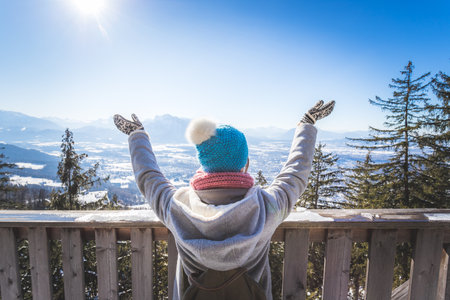 Back of young woman who is raising her hands on the mountain, outlook. Gaisberg, Austriaの写真素材