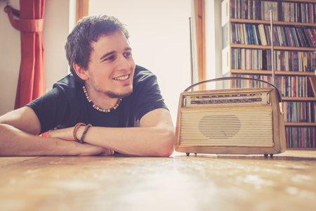 Young man listing to an retro radioの写真素材