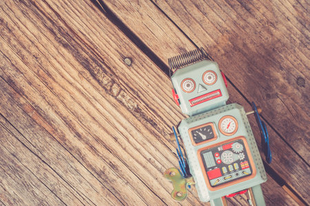 Robot toy, symbol for a chatbot or social bot and algorithms. Wood texture.