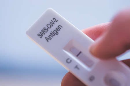Close up of fingers holding express antigen test, negative resultの写真素材