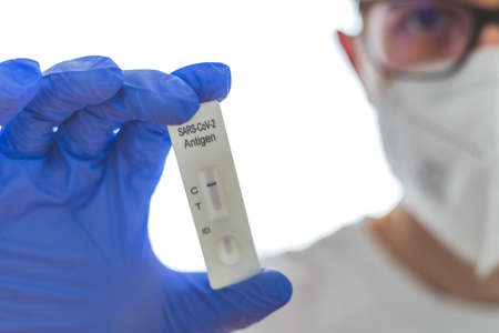 Close up of antigen corona or covid-19 test in the fingers of a young biologist or pharmacistの写真素材