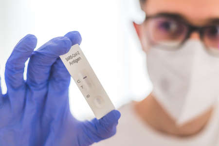 Close up of antigen corona or covid-19 test in the fingers of a young biologist or pharmacistの写真素材