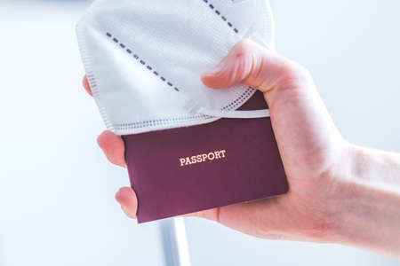 Close up of fingers holding a passport for traveling, airport, âpassportâ, ffp2 protection maskの写真素材