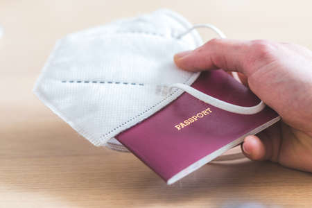 Close up of fingers holding a passport for traveling, airport, âpassportâ, ffp2 protection maskの写真素材