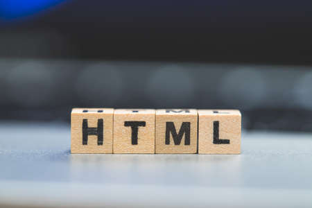 Wooden cubes with the letters âHTMLâ are lying on a laptopの写真素材