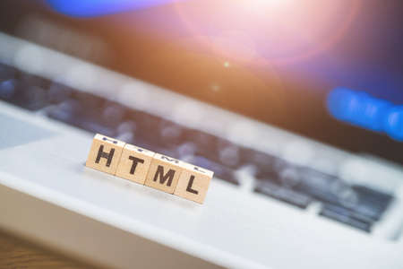 Wooden cubes with the letters âHTMLâ are lying on a laptopの写真素材