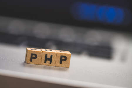 Wooden cubes with the letters âPHPâ are lying on a laptopの写真素材