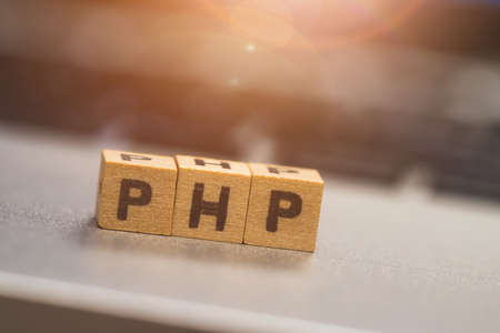 Wooden cubes with the letters â€œPHPâ€ are lying on a laptop