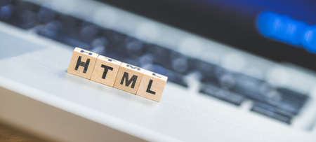 Wooden cubes with the letters âHTMLâ are lying on a laptopの写真素材