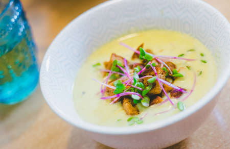 Close up of fresh broccoli soup with crunchy croutons and radish sprouts in white ceramic bowlの写真素材