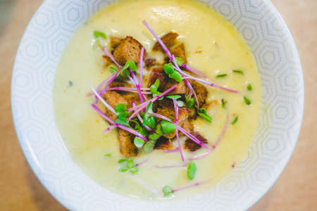 Close up of fresh broccoli soup with crunchy croutons and radish sprouts in white ceramic bowlの写真素材