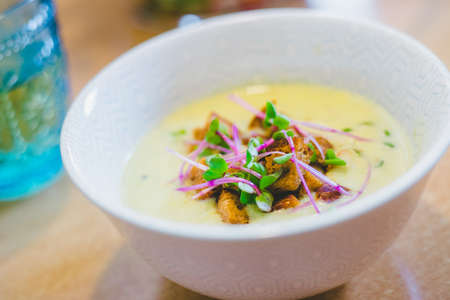 Close up of fresh broccoli soup with crunchy croutons and radish sprouts in white ceramic bowlの写真素材