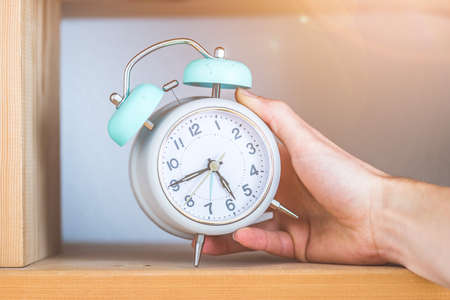 Retro styled white alarm clock in the wooden bookshelfの写真素材