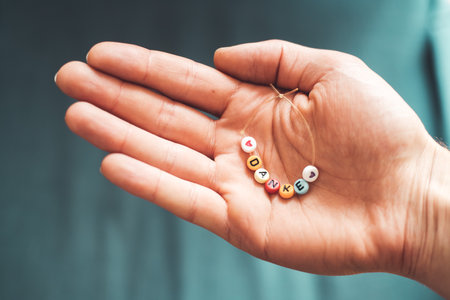 Close up of hand holding a bracelet made out of letters with the word âDankeâ, close upの写真素材