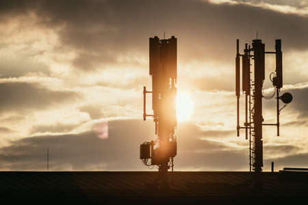 Silhouette of communication or cell tower on the rooftop of a building, evening sunshineの写真素材