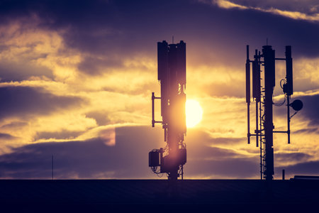 Silhouette of communication or cell tower on the rooftop of a building, evening sunshineの写真素材
