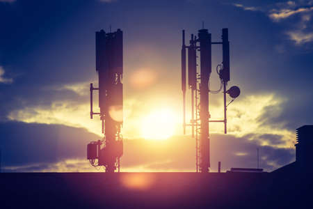 Silhouette of communication or cell tower on the rooftop of a building, evening sunshineの写真素材