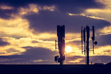 Silhouette of communication or cell tower on the rooftop of a building, evening sunshineの写真素材