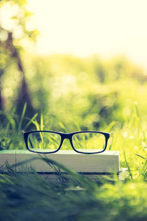 Black glasses and book outdoors in the park, summer timeの写真素材
