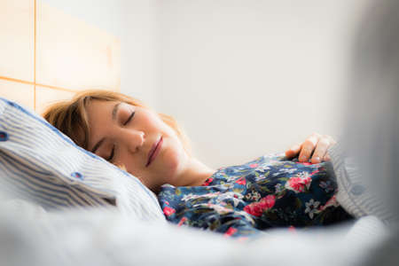 Young woman sleeping peacefully in her bedroom, dayの写真素材