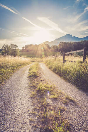 Scenic sunset view over country road, meadow, hills and mountains.の写真素材