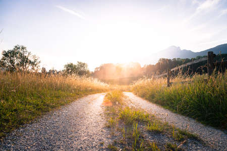 Scenic sunset view over country road, meadow, hills and mountains.の写真素材