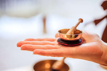 Small singing bowl holding in hand, blurry backgroundの写真素材