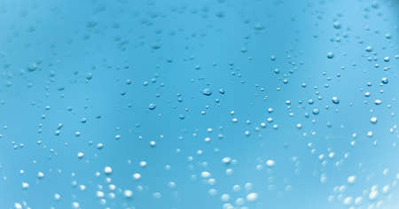 Close up picture of water drops on the window. Blue sky and clouds in the background.の写真素材
