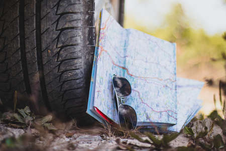 Car tire, sunglasses and roadmap on sandy ground, desertの写真素材