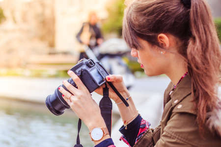 Young beautiful girl is taking a picture with her camera. View from behind.の写真素材