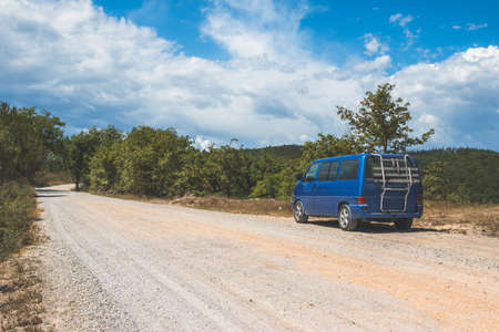 Retro minivan car standing on side of the desert road in the wildernessの写真素材